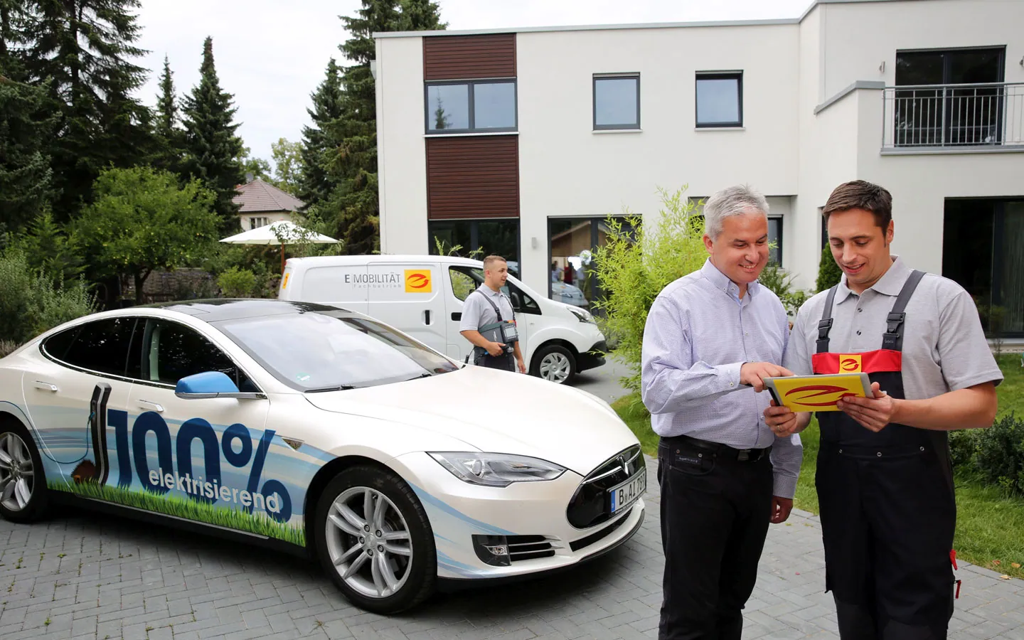 E-Mobilität - Mitarbeiter mit Kunden vor Elektrofahrzeugen 100% elektrisch · Winter Elektro